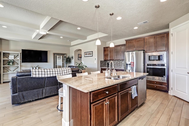 6240 Redroot St, Albuquerque, NM 87120 - kitchen featuring appliances with stainless steel finishes, a sink, arched walkways, light wood-style floors, and a kitchen breakfast bar