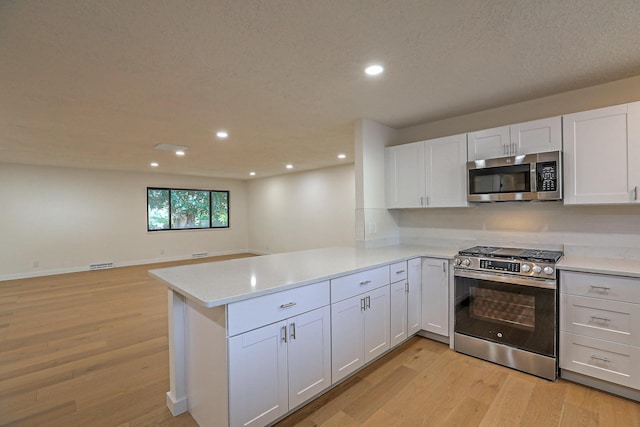 3217 Tennessee St NE, Albuquerque, NM 87110 - kitchen featuring appliances with stainless steel finishes, a peninsula, light wood-style flooring, recessed lighting, and white cabinets