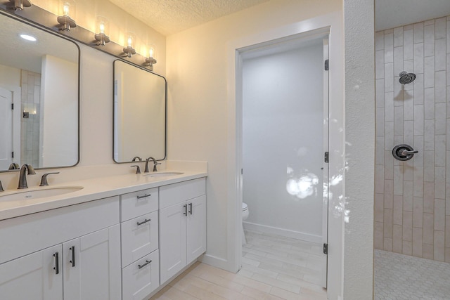 3217 Tennessee St NE, Albuquerque, NM 87110 - bathroom featuring walk in shower, double vanity, toilet, and a textured ceiling