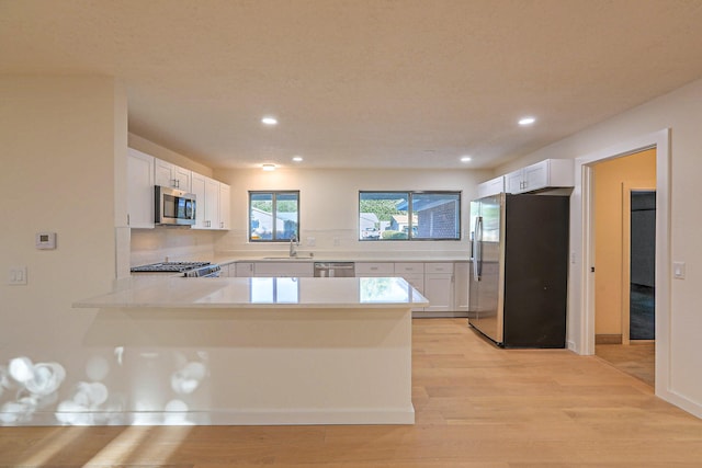 3217 Tennessee St NE, Albuquerque, NM 87110 - kitchen with appliances with stainless steel finishes, a sink, light countertops, a peninsula, and white cabinets