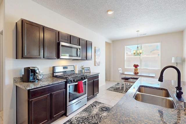 2317 Solara Loop NE, Rio Rancho, NM 87144 - kitchen with appliances with stainless steel finishes, a chandelier, dark brown cabinetry, light tile patterned flooring, and a textured ceiling