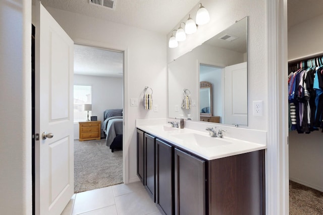 2317 Solara Loop NE, Rio Rancho, NM 87144 - full bath with connected bathroom, double vanity, tile patterned flooring, a walk in closet, and a textured ceiling