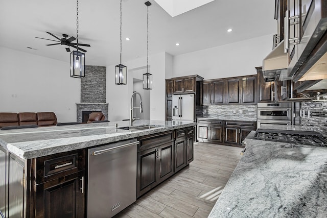 11 Del Cerro Ct, Los Lunas, NM 87031 - kitchen featuring appliances with stainless steel finishes, a sink, open floor plan, tasteful backsplash, and an island with sink