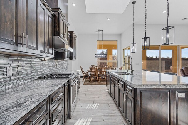11 Del Cerro Ct, Los Lunas, NM 87031 - kitchen with stainless steel appliances, a sink, backsplash, light stone counters, and a center island with sink
