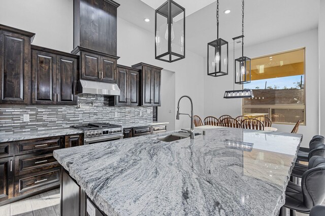 11 Del Cerro Ct, Los Lunas, NM 87031 - kitchen featuring a sink, high end stainless steel range oven, under cabinet range hood, a kitchen bar, and decorative backsplash