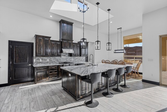 11 Del Cerro Ct, Los Lunas, NM 87031 - kitchen with a breakfast bar, light wood-style floors, an island with sink, a sink, and tasteful backsplash