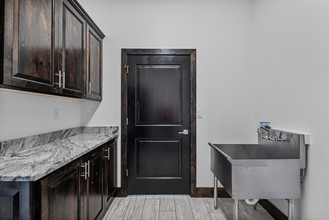 11 Del Cerro Ct, Los Lunas, NM 87031 - kitchen featuring dark brown cabinetry, light wood finished floors, a sink, and baseboards