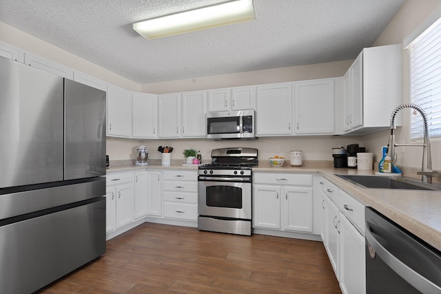8331 Wild Dunes Ave NW, Albuquerque, NM 87120 - kitchen with stainless steel appliances, a sink, light countertops, white cabinets, and dark wood-style flooring