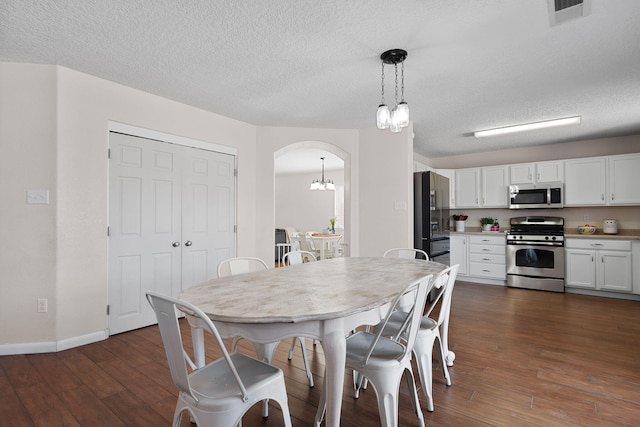8331 Wild Dunes Ave NW, Albuquerque, NM 87120 - dining area featuring a chandelier, dark wood-style floors, arched walkways, baseboards, and a textured ceiling