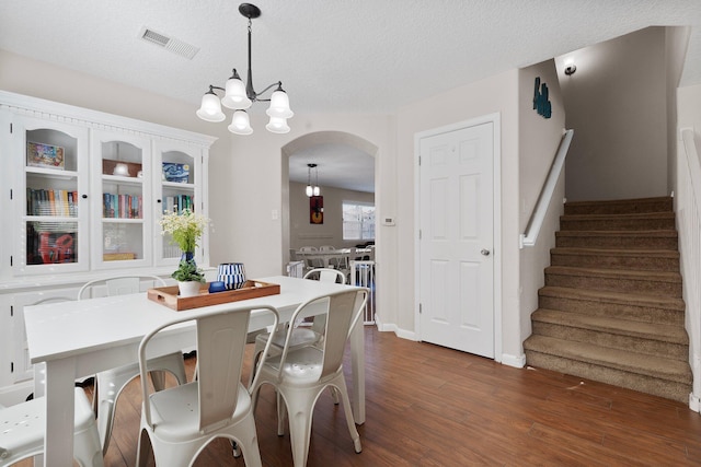 8331 Wild Dunes Ave NW, Albuquerque, NM 87120 - dining area with arched walkways, stairs, dark wood-type flooring, a chandelier, and a textured ceiling