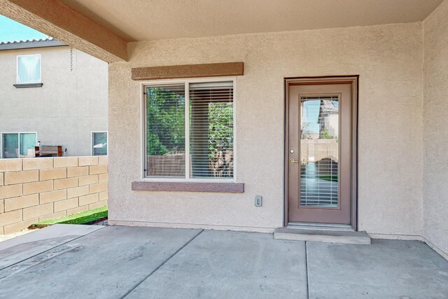 9624 Basalt Peak Dr NW, Albuquerque, NM 87114 - view of exterior entry with stucco siding and a patio