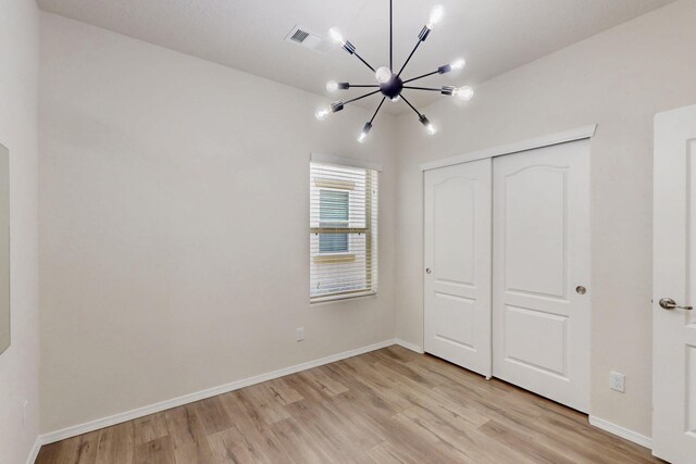 9624 Basalt Peak Dr NW, Albuquerque, NM 87114 - unfurnished bedroom with a chandelier, light wood finished floors, and a closet