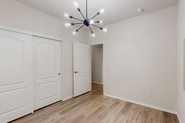 9624 Basalt Peak Dr NW, Albuquerque, NM 87114 - unfurnished bedroom with a chandelier, light wood-style flooring, a closet, and baseboards