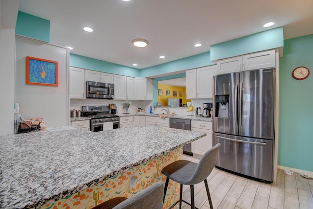 10008 Propps St NE, Albuquerque, NM 87112 - kitchen featuring stainless steel appliances, a kitchen bar, white cabinetry, a peninsula, and light stone countertops