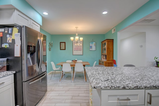 10008 Propps St NE, Albuquerque, NM 87112 - kitchen with stainless steel fridge, a chandelier, white cabinetry, recessed lighting, and light stone counters