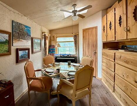 34 Halcon Rd, Ramah, NM 87321 - dining space with light wood-style flooring, ceiling fan, baseboards, vaulted ceiling, and a textured wall
