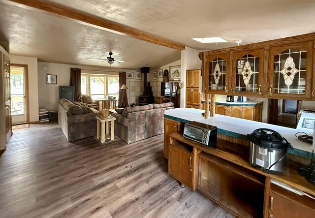 34 Halcon Rd, Ramah, NM 87321 - kitchen featuring brown cabinets, a wood stove, wood finished floors, and glass insert cabinets