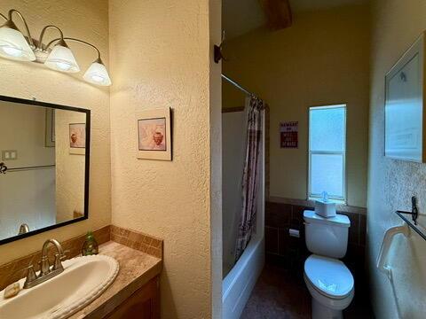 34 Halcon Rd, Ramah, NM 87321 - full bath with vanity, toilet, a textured wall, and shower / bath combo