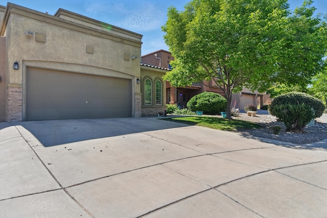 2115 Cortina Loop SE, Rio Rancho, NM 87124 - view of front facade featuring stone siding, concrete driveway, stucco siding, and a garage