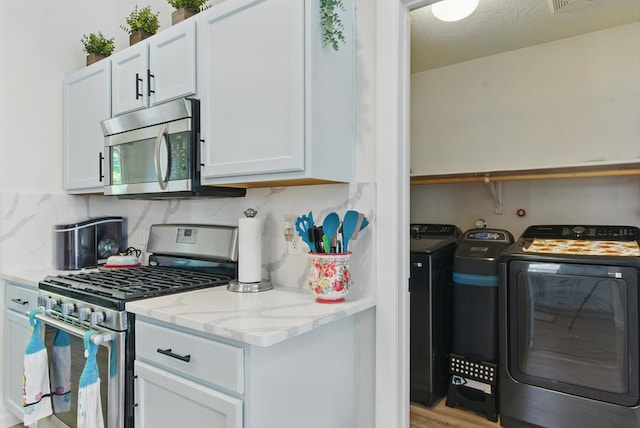 2115 Cortina Loop SE, Rio Rancho, NM 87124 - kitchen with stainless steel appliances, washing machine and dryer, light stone countertops, white cabinets, and decorative backsplash