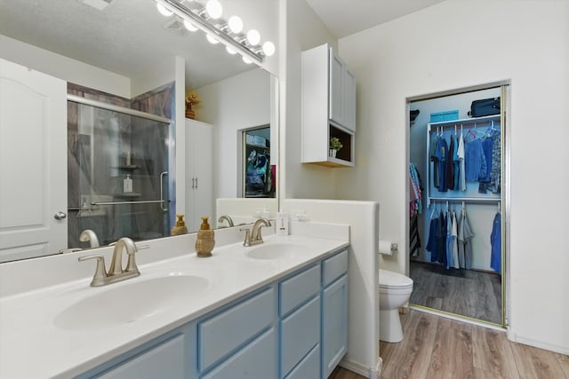2115 Cortina Loop SE, Rio Rancho, NM 87124 - bathroom with double vanity, toilet, a stall shower, wood finished floors, and a spacious closet