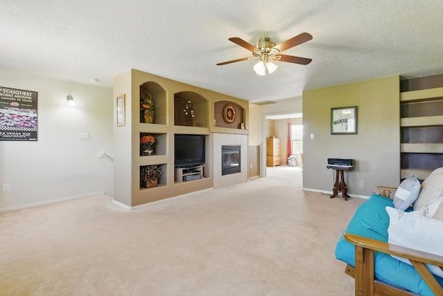2115 Cortina Loop SE, Rio Rancho, NM 87124 - carpeted living area featuring a textured ceiling, a tiled fireplace, a ceiling fan, and baseboards