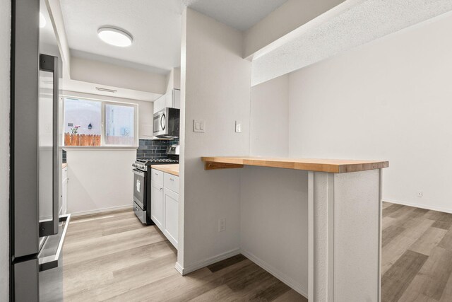 1616 Vail Pl SE, Albuquerque, NM 87106 - kitchen with stainless steel appliances, wooden counters, light wood-type flooring, and white cabinetry