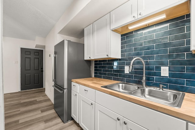 1616 Vail Pl SE, Albuquerque, NM 87106 - kitchen featuring butcher block counters, freestanding refrigerator, white cabinets, light wood finished floors, and a sink