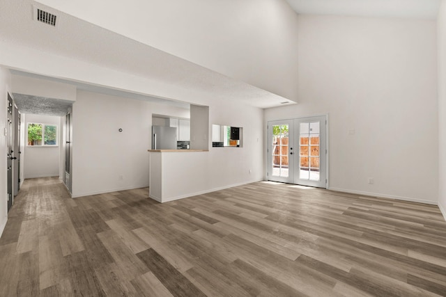 1616 Vail Pl SE, Albuquerque, NM 87106 - unfurnished living room featuring light wood-type flooring, french doors, baseboards, and a towering ceiling