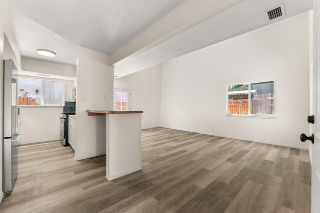 1616 Vail Pl SE, Albuquerque, NM 87106 - kitchen featuring stainless steel appliances, light wood-style floors, a textured ceiling, baseboards, and a peninsula