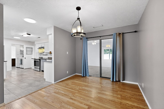 2110 Twisted Juniper Rd SE, Rio Rancho, NM 87124 - unfurnished room with a textured ceiling, light wood-style flooring, baseboards, and a chandelier