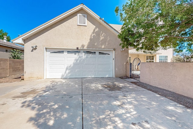 717 Monterrey Rd NE, Rio Rancho, NM 87144 - view of front of home with stucco siding, driveway, an attached garage, and a gate