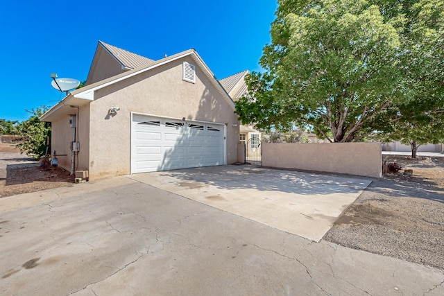 717 Monterrey Rd NE, Rio Rancho, NM 87144 - view of home's exterior with stucco siding, an attached garage, driveway, and a gate