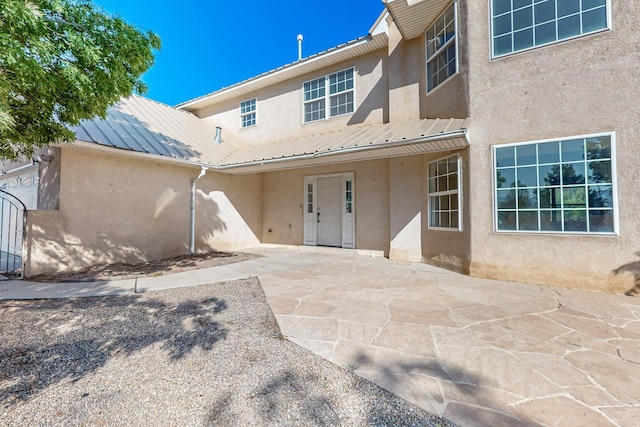 717 Monterrey Rd NE, Rio Rancho, NM 87144 - rear view of house featuring stucco siding, a patio, and a metal roof