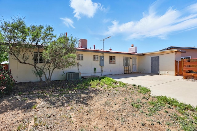2724 Pennsylvania St NE, Albuquerque, NM 87110 - back of house featuring stucco siding, a patio, central air condition unit, and a chimney