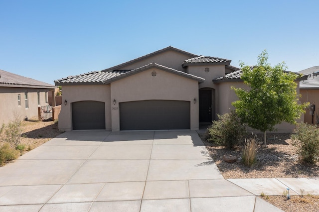 7037 Cleary Loop NE, Rio Rancho, NM 87144 - mediterranean / spanish home with an attached garage, a tile roof, driveway, and stucco siding