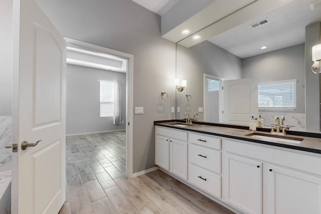 7037 Cleary Loop NE, Rio Rancho, NM 87144 - bathroom featuring double vanity, plenty of natural light, recessed lighting, wood finished floors, and baseboards