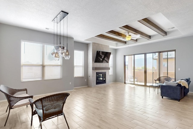 7037 Cleary Loop NE, Rio Rancho, NM 87144 - living area with baseboards, a textured ceiling, beamed ceiling, a tile fireplace, and a ceiling fan