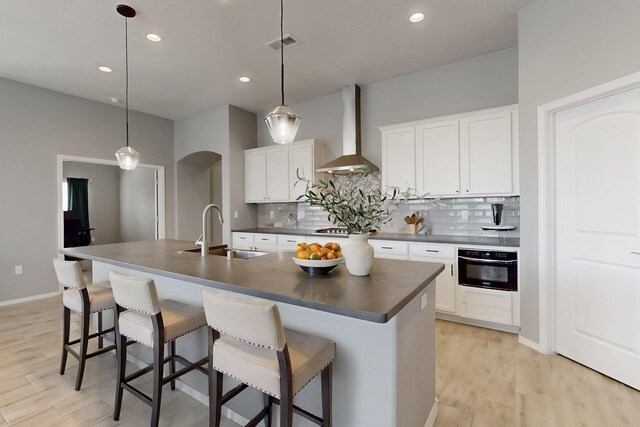 7037 Cleary Loop NE, Rio Rancho, NM 87144 - kitchen with a sink, wall chimney exhaust hood, dark countertops, black oven, and tasteful backsplash