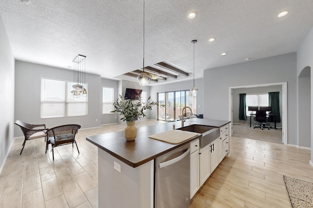 7037 Cleary Loop NE, Rio Rancho, NM 87144 - kitchen featuring stainless steel dishwasher, a sink, a center island with sink, a textured ceiling, and open floor plan