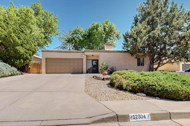 12304 Phoenix Ave NE, Albuquerque, NM 87112 - pueblo revival-style home featuring stucco siding, a garage, driveway, and a chimney