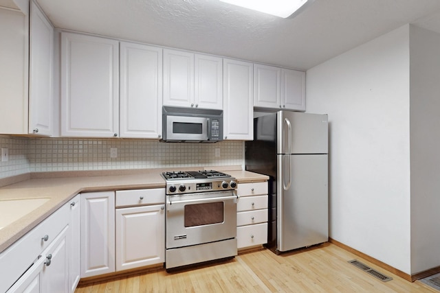 12304 Phoenix Ave NE, Albuquerque, NM 87112 - kitchen with stainless steel appliances, light wood-style flooring, tasteful backsplash, and white cabinets