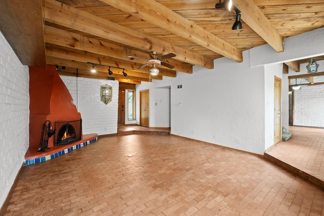 234 Horton Ln NW, Albuquerque, NM 87114 - unfurnished living room featuring brick flooring, wooden ceiling with exposed beams, a ceiling fan, a lit fireplace, and baseboards