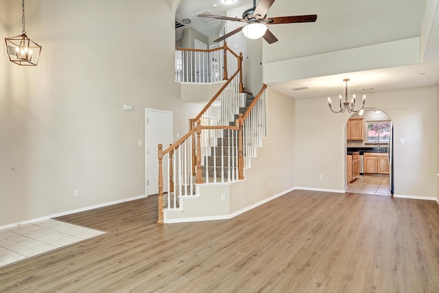 6923 Luz Del Sol Pl NW, Albuquerque, NM 87114 - unfurnished living room with a chandelier, ceiling fan, stairway, light wood-style floors, and a high ceiling