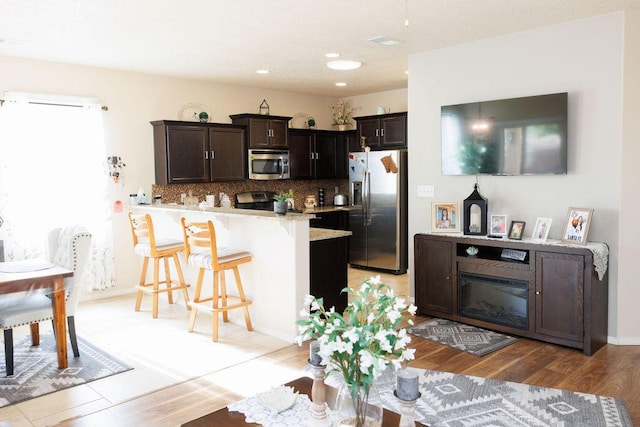 1019 Jacobs Dr NE, Rio Rancho, NM 87144 - kitchen featuring stainless steel appliances, a breakfast bar, a peninsula, light countertops, and dark brown cabinets