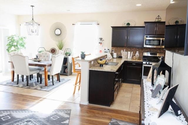 1019 Jacobs Dr NE, Rio Rancho, NM 87144 - kitchen with stainless steel appliances, a chandelier, a peninsula, healthy amount of natural light, and recessed lighting