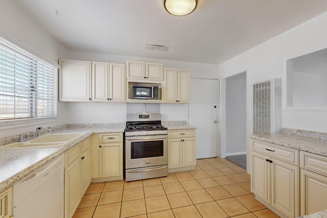 9913 Leyendecker Rd NE, Albuquerque, NM 87112 - kitchen with stainless steel appliances, cream cabinets, a sink, and light tile patterned floors