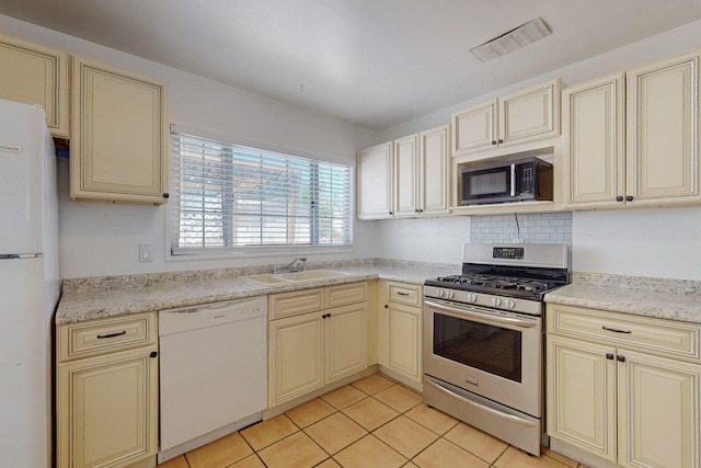 9913 Leyendecker Rd NE, Albuquerque, NM 87112 - kitchen with cream cabinets, appliances with stainless steel finishes, a sink, and light tile patterned floors