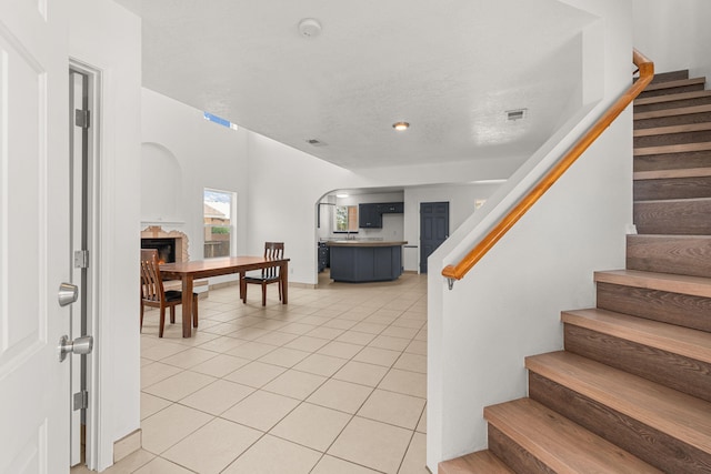 10504 W Connemara Ave SW, Albuquerque, NM 87121 - staircase with arched walkways, tile patterned floors, and a fireplace