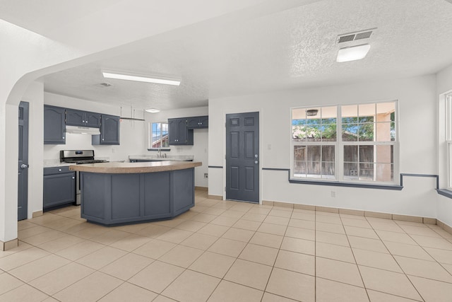 10504 W Connemara Ave SW, Albuquerque, NM 87121 - kitchen featuring stainless steel gas stove, under cabinet range hood, light countertops, a textured ceiling, and a kitchen island